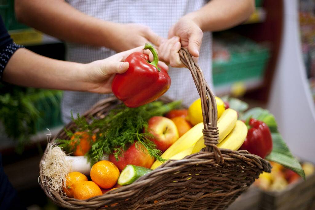 A split-screen image showing a rushed delivery app order on one side and carefully selected fresh groceries on the other. The image highlights quality and personal care.