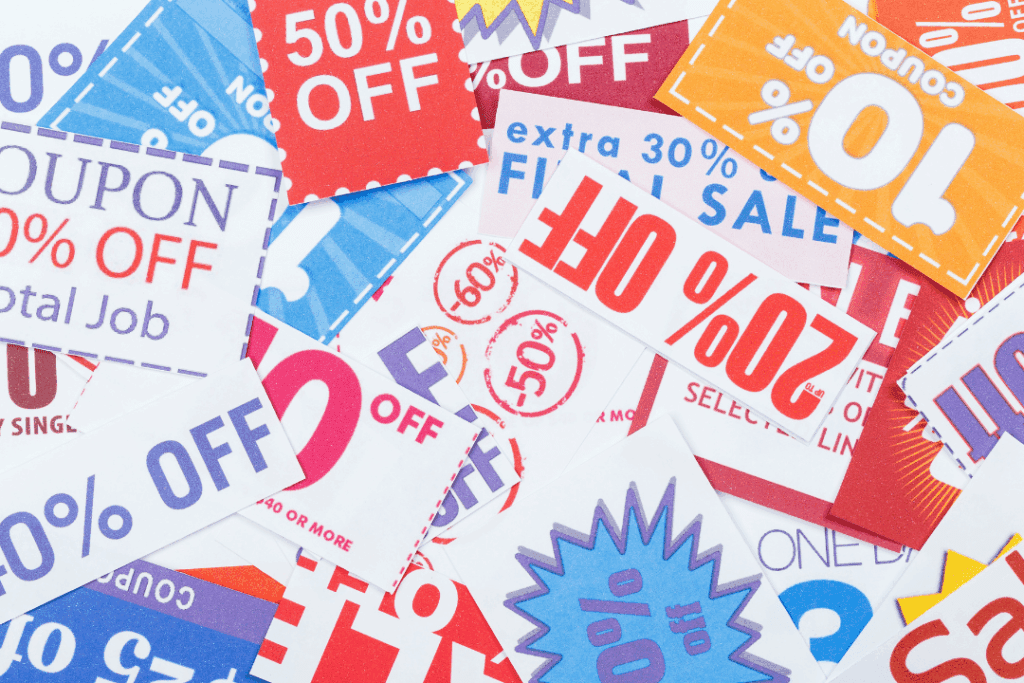 A close-up of a personal shopper’s hand checking a grocery list with notes about substitutions and clipped coupons beside a cart. The image suggests attention to detail and customized service.