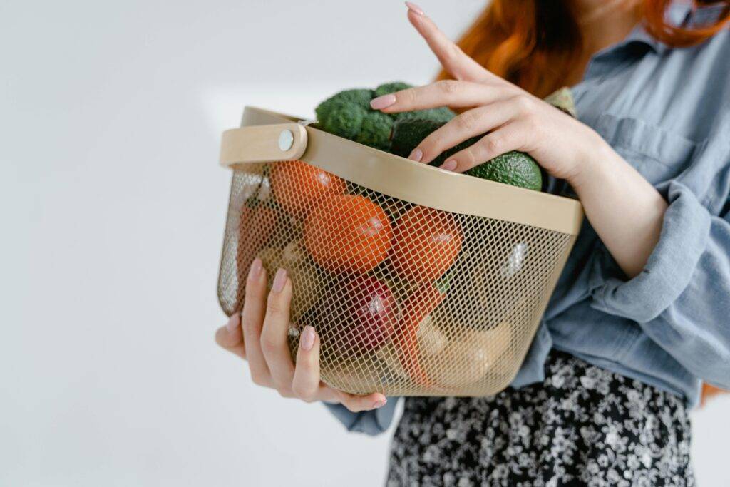 A reusable grocery bag filled with essentials like milk, bread, fruit, and snacks, sitting on a kitchen counter beside a printed checklist. The image conveys organization and convenience for family life.