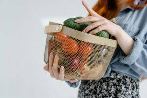 A reusable grocery bag filled with essentials like milk, bread, fruit, and snacks, sitting on a kitchen counter beside a printed checklist. The image conveys organization and convenience for family life.
